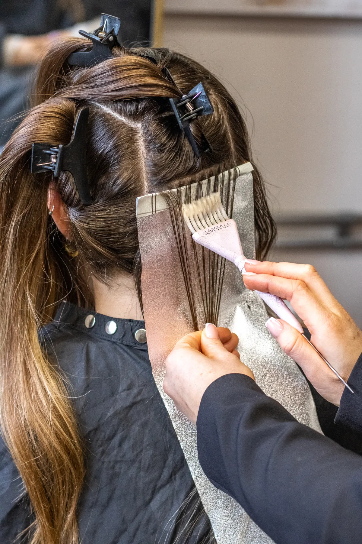 Lisa brengt zorgvuldig kleur aan met folies tijdens een behandeling